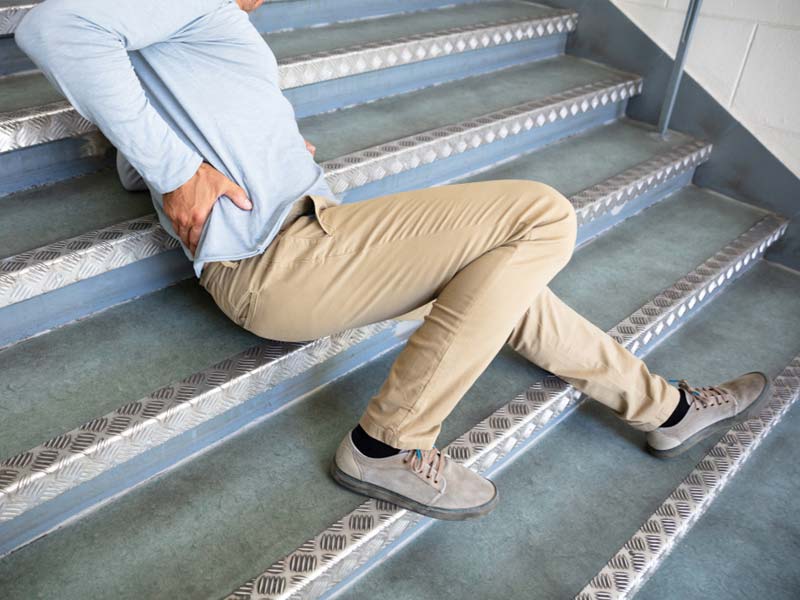 A man holding his lower back after falling on stairs