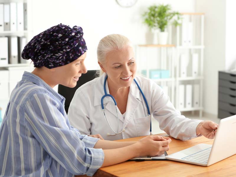 A doctor and a cancer patient smiling and looking at laptop