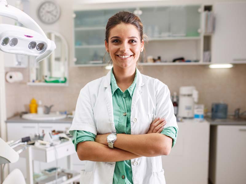 A friendly looking dentist woman with folded arms looking at camera