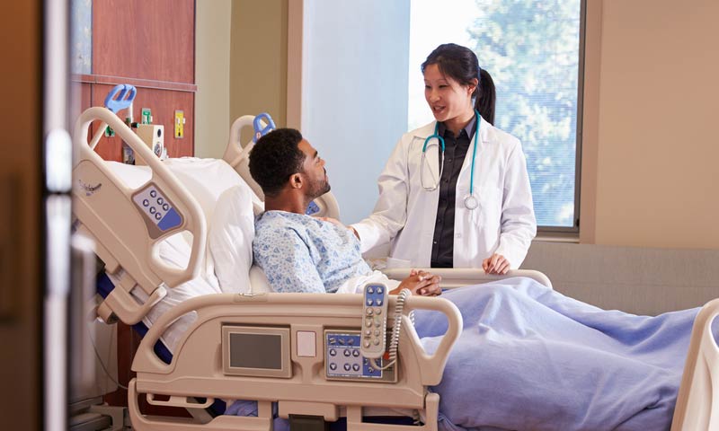 Doctor sitting bedside with elderly patient and her daughter