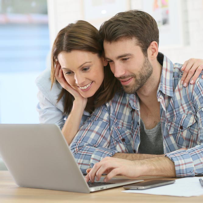 Man and woman smiling and looking at laptop